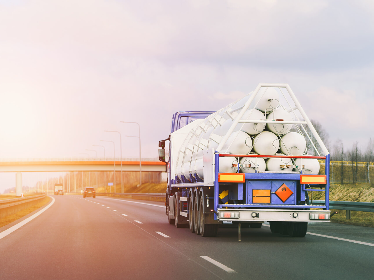 Truck transporting large rolls of material on highway during sunrise