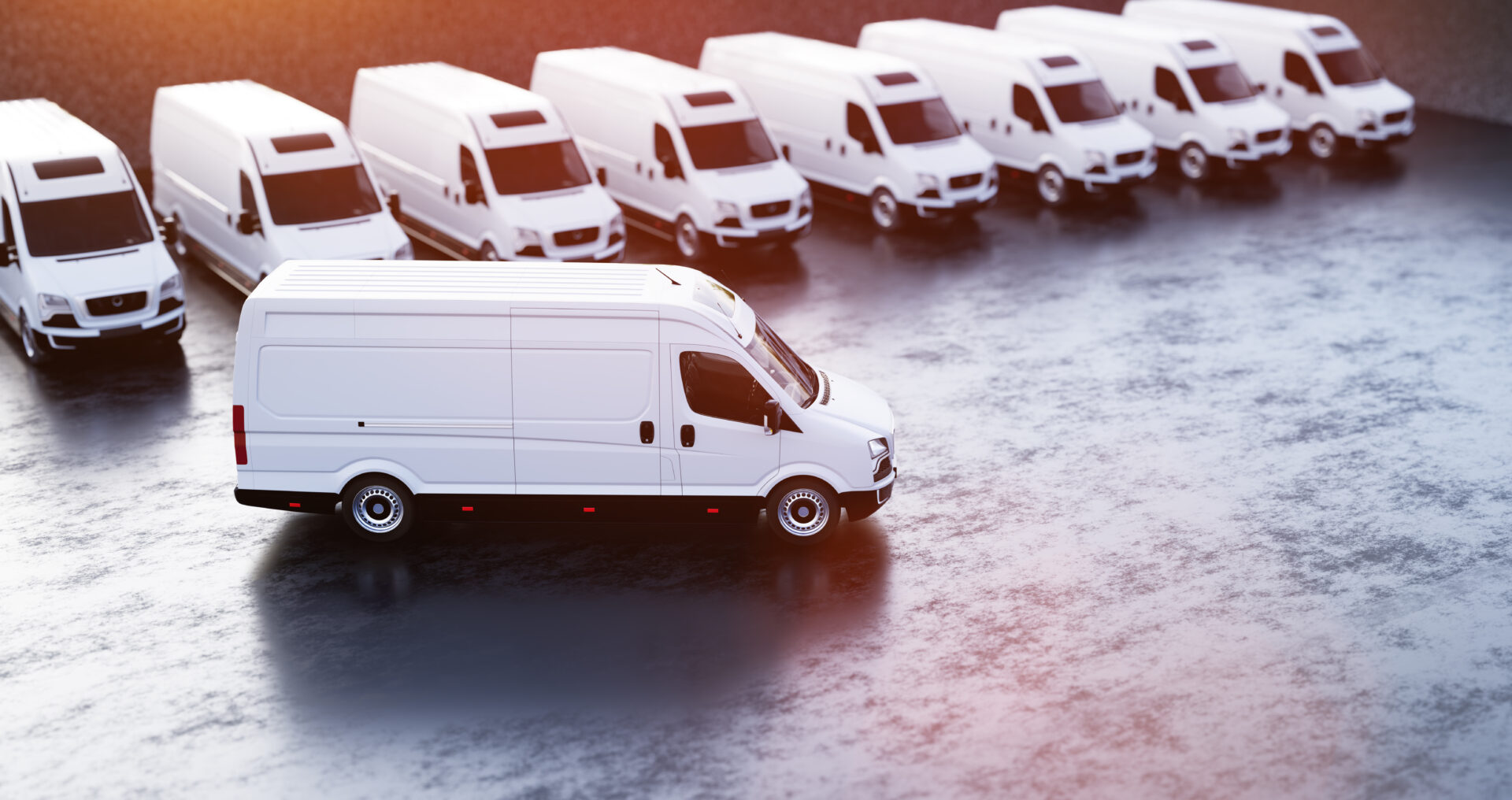 White delivery vans lined up on wet pavement, one van prominent in foreground