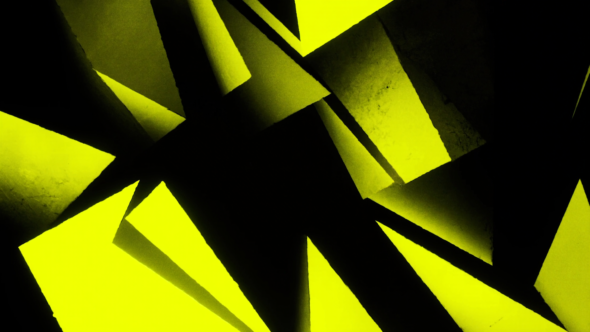 Bright yellow geometric shapes with sharp shadows on black background