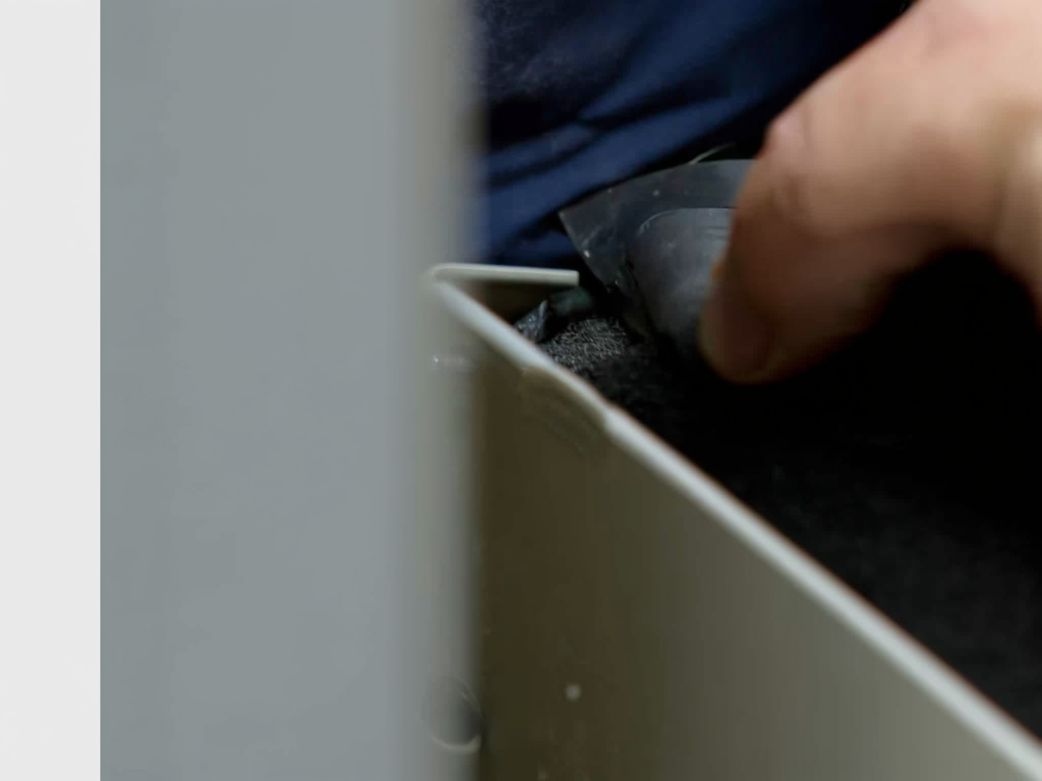 Close-up of hands using a tool to install or adjust something on a white surface
