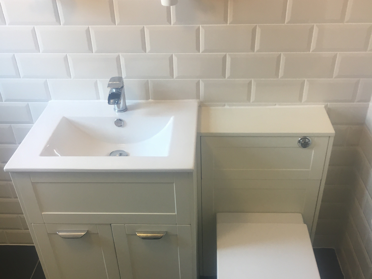 Modern bathroom with white vanity sink, faucet, white subway tile backsplash, and toilet