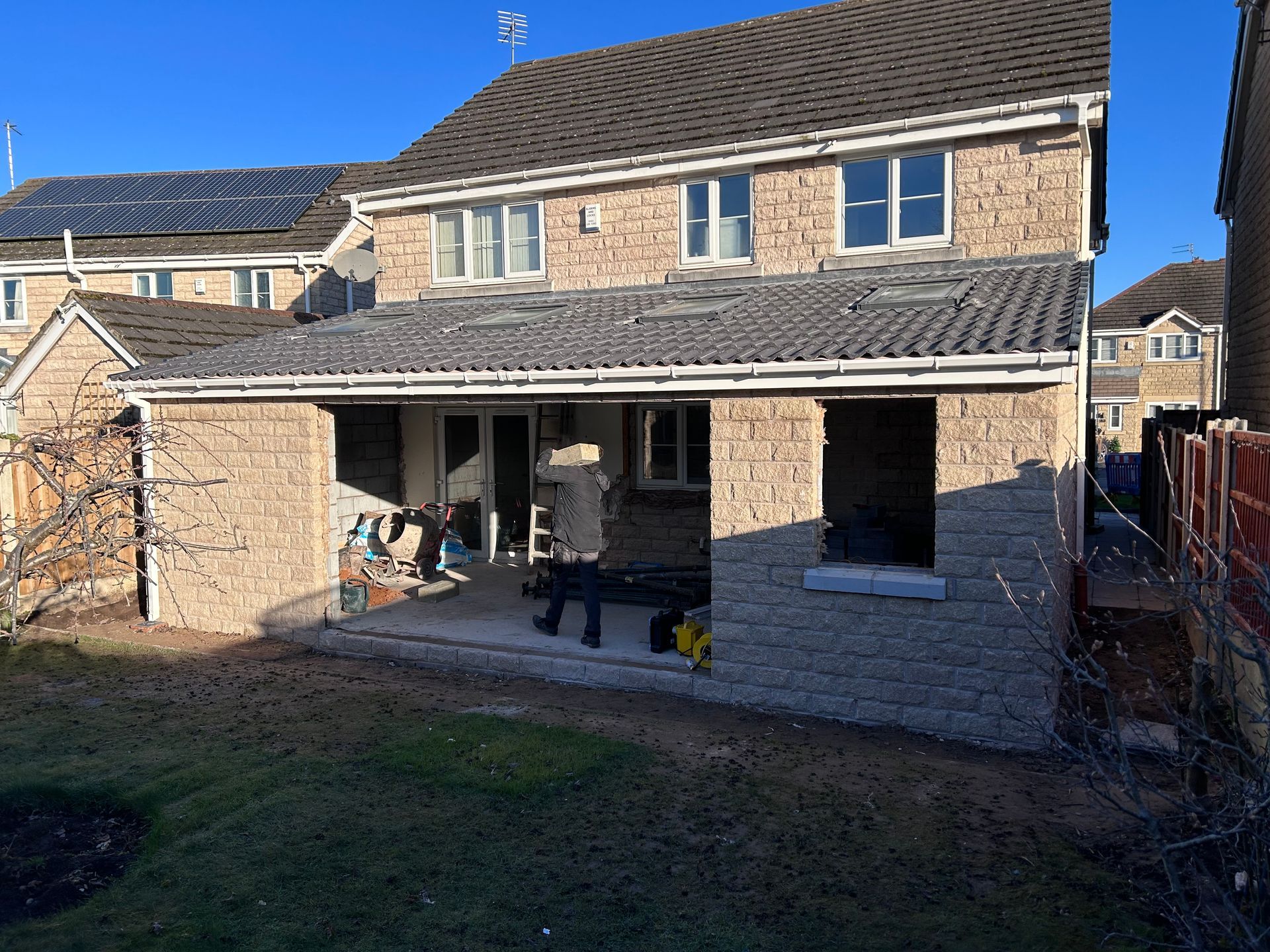 Stone house with new single-story extension under construction, open framework visible