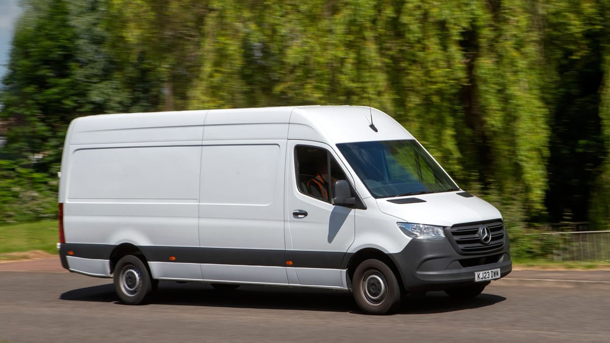 White Mercedes-Benz commercial van parked in profile view against green trees