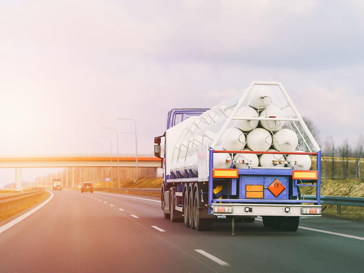 Truck with white cargo on highway driving into sunset light