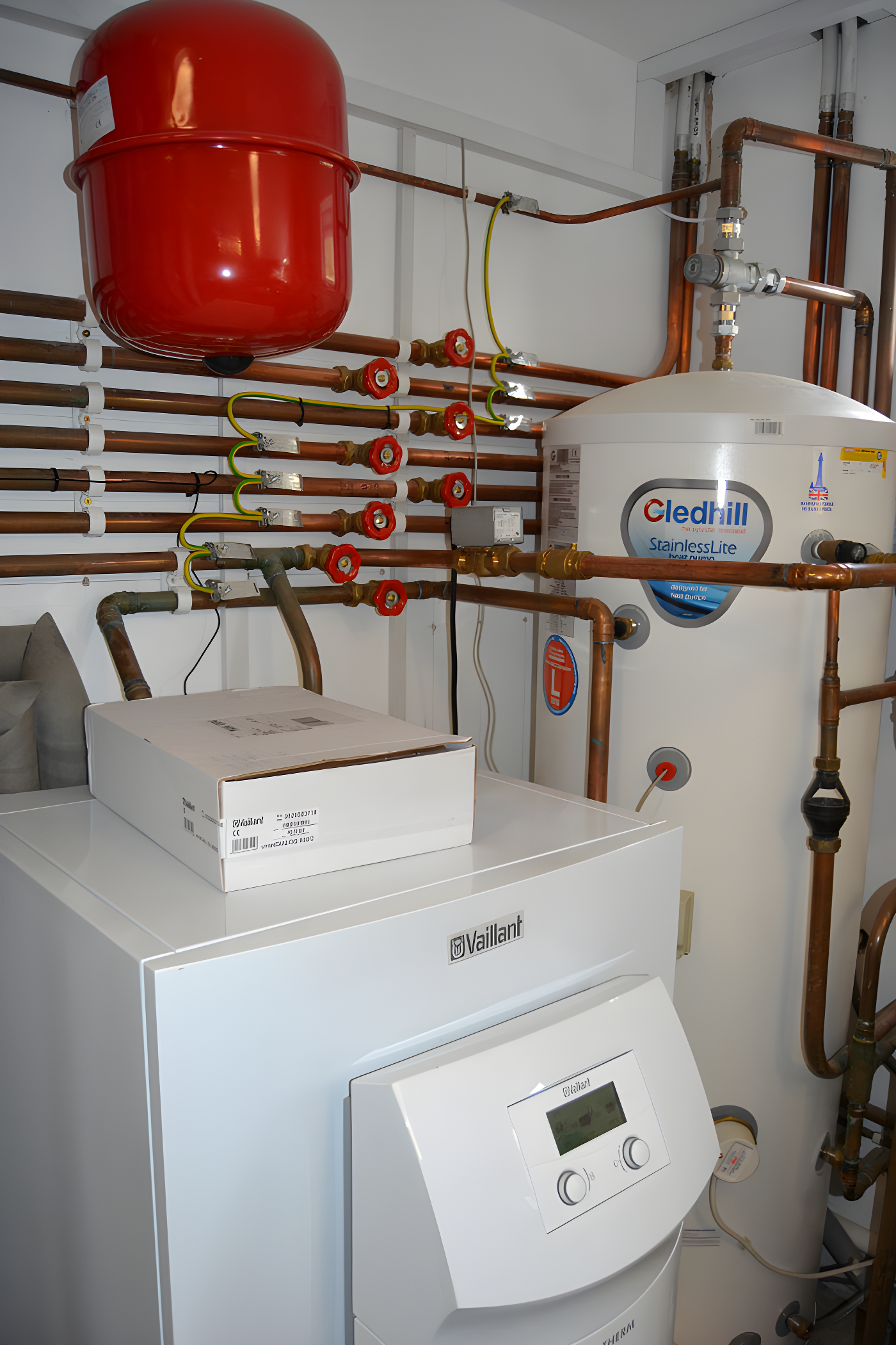 Heating system installation with red expansion tank, Cledhill water tank, Vaillant boiler, and copper pipework