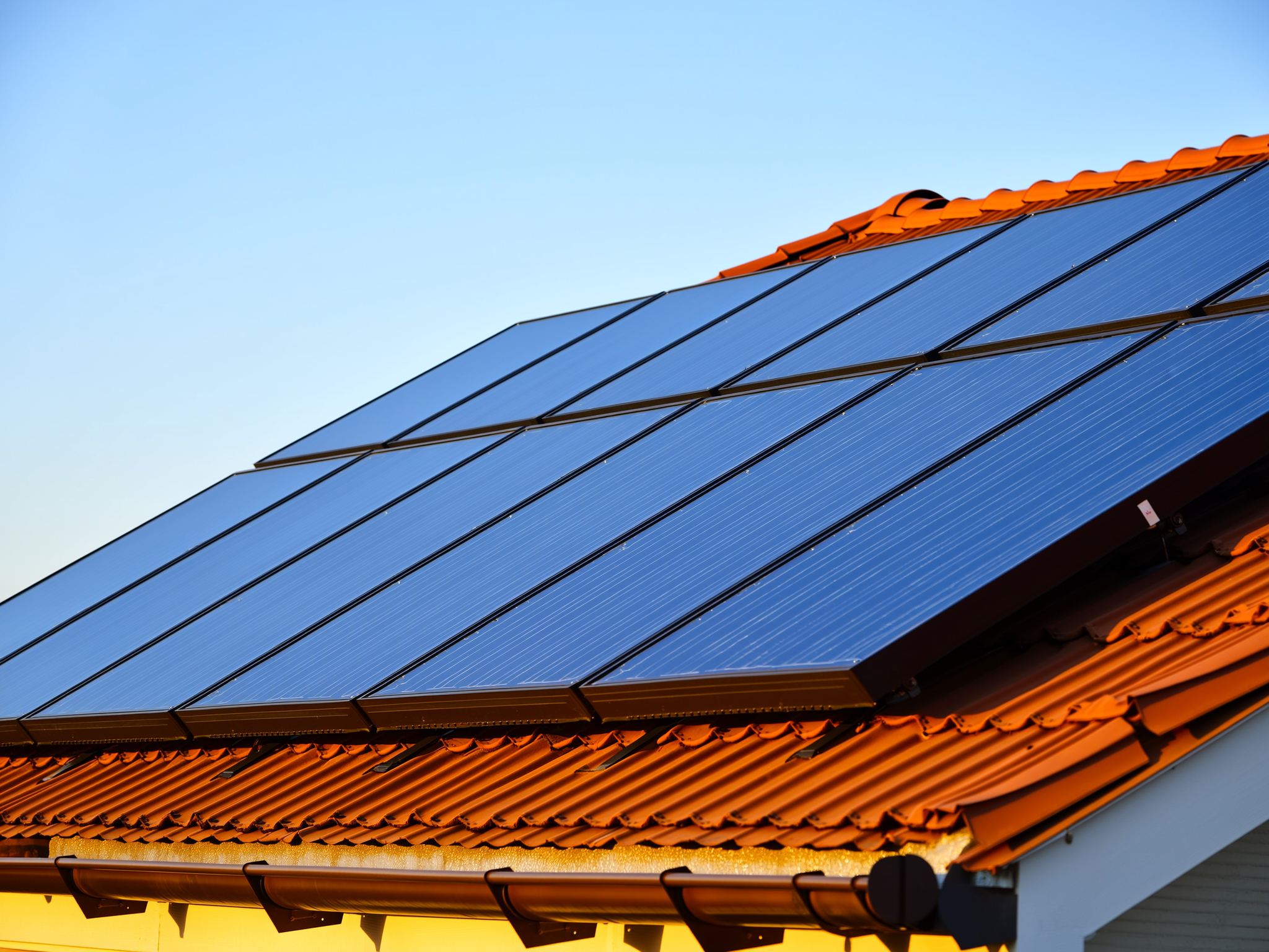 Blue solar photovoltaic panels installed on residential roof with orange tile