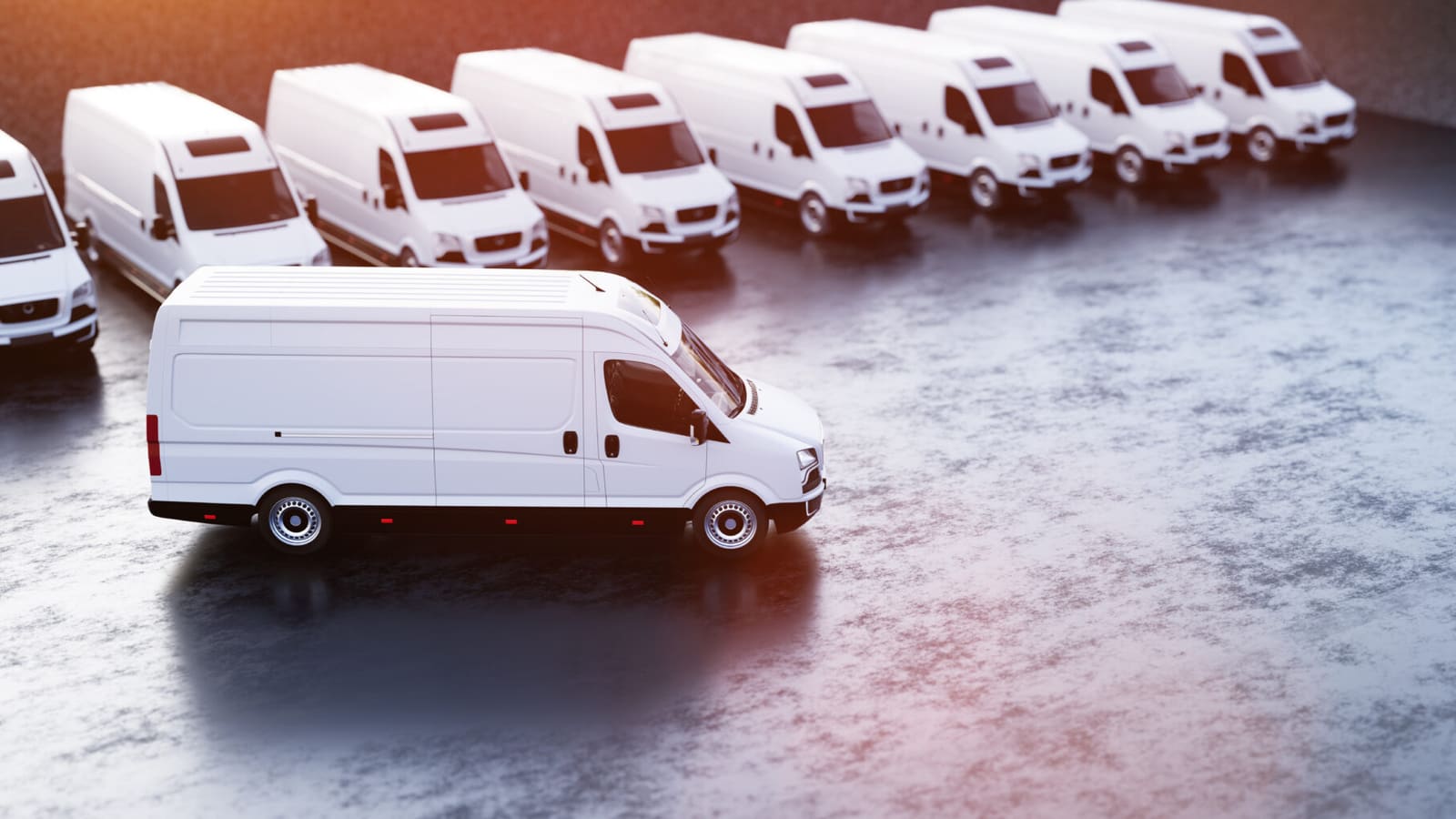 White delivery vans lined up in a row on a concrete surface