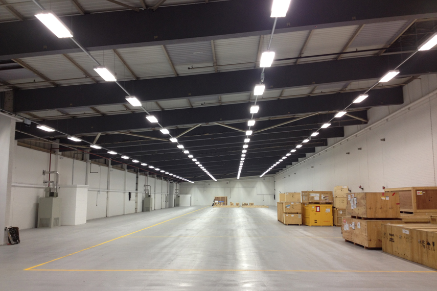 Empty warehouse interior with linear LED ceiling lights and stacked cardboard boxes