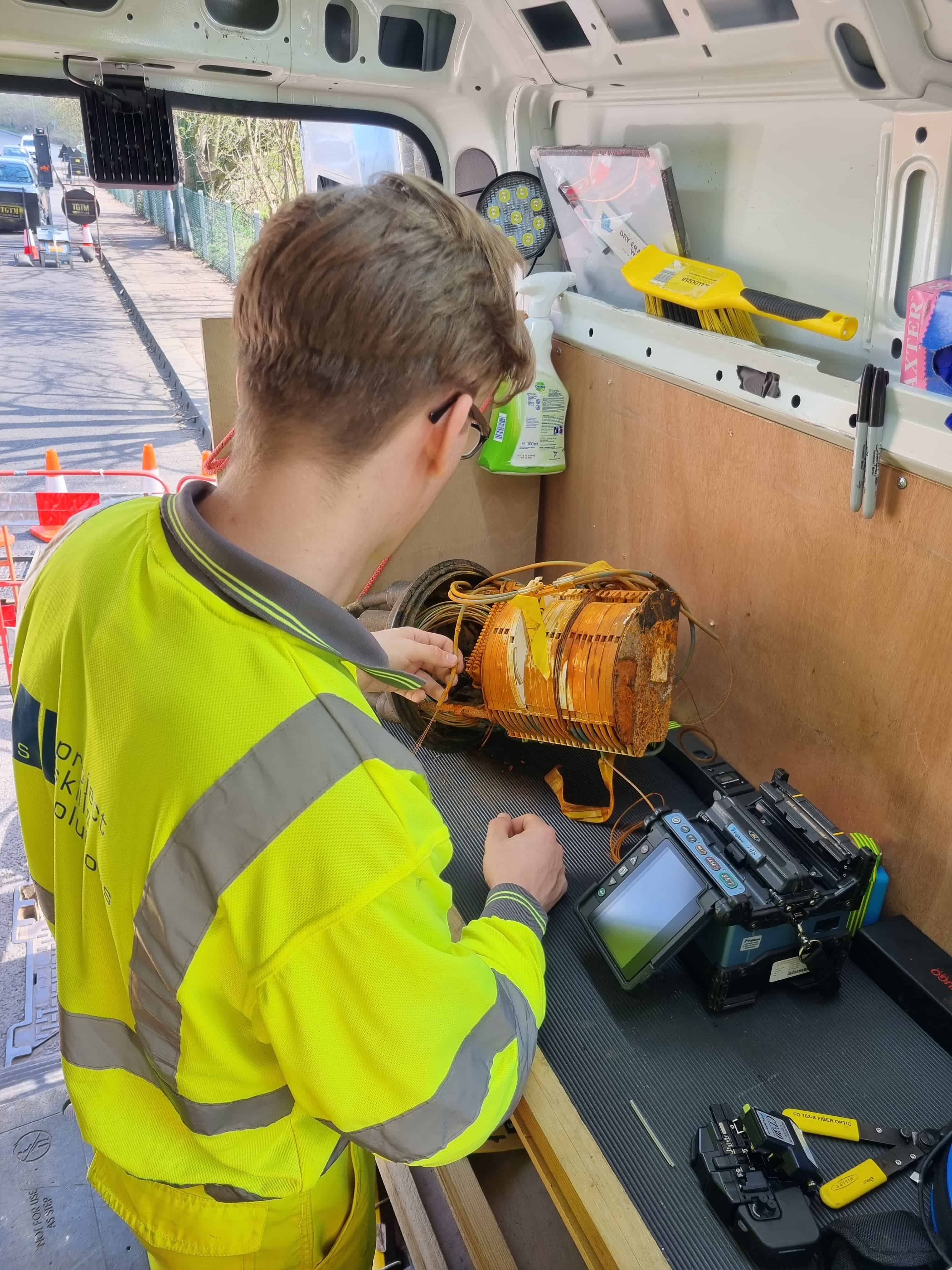 Technician in high-visibility gear working with electrical equipment inside service van