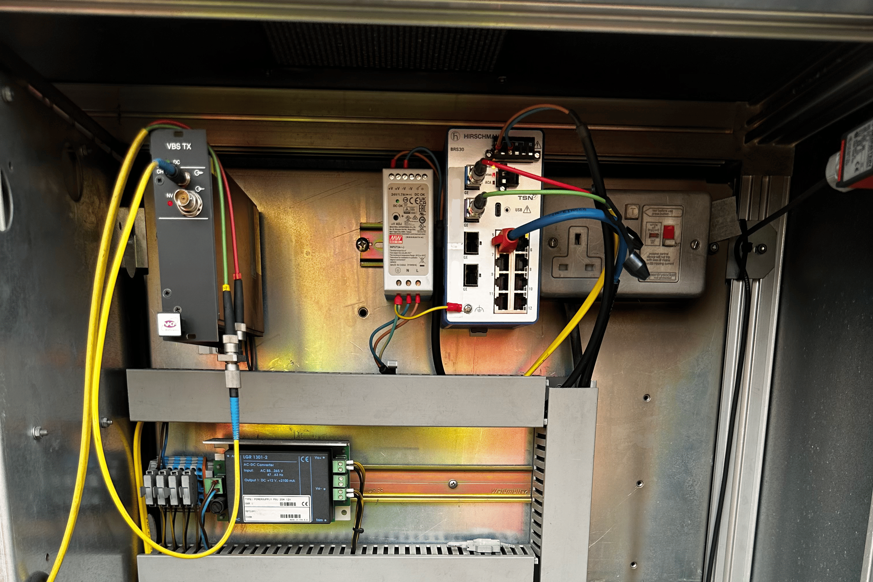 Industrial electrical control panel with power supplies, networking equipment, and yellow cables